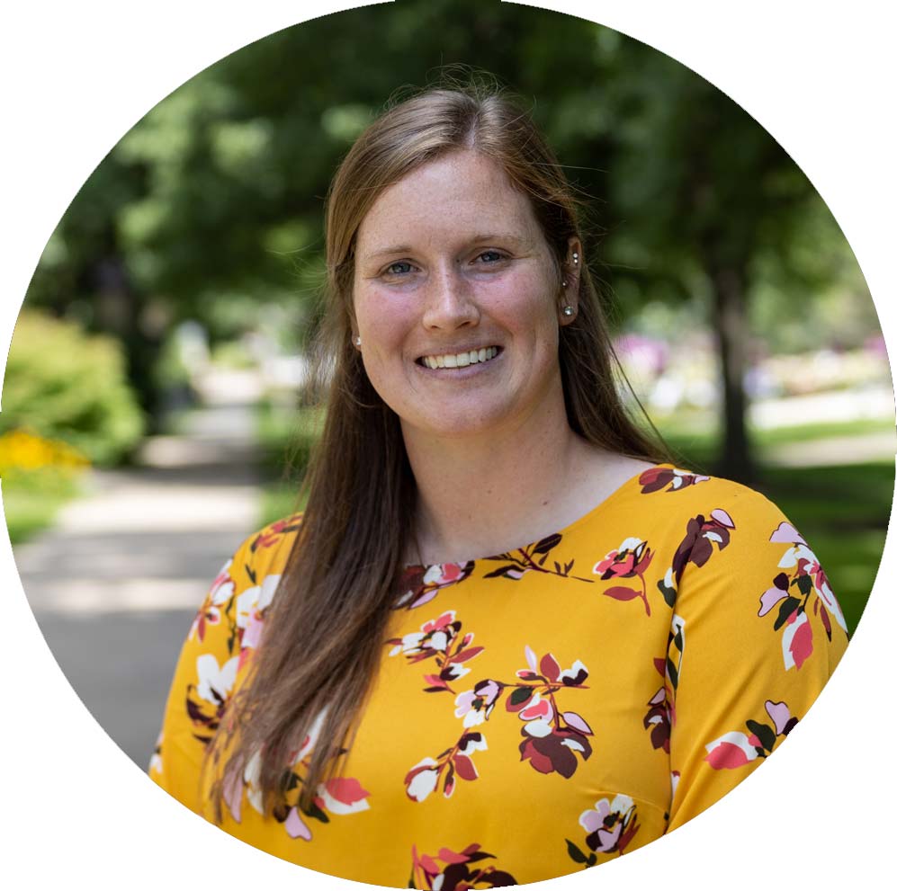 Staff member Katie Govan with gold floral shirt standing on campus.