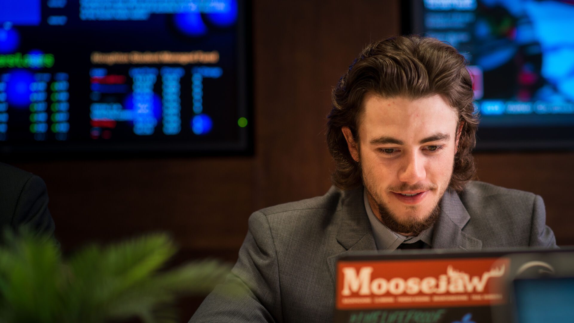 Houghton business student sitting in the investment center with laptop.