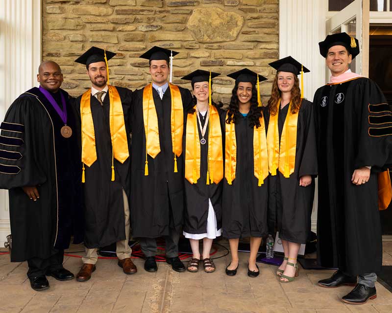 Houghton University's class of 2023 valedictorians stand with president Wayne Lewis and provost David Davies