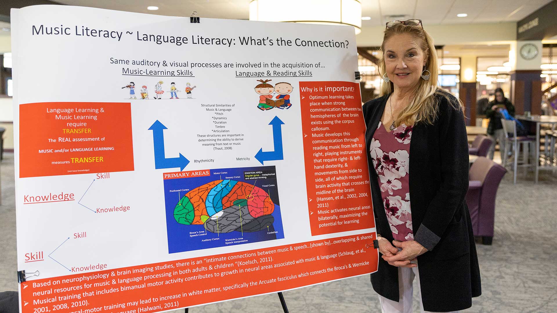 Professor Sara Massey standing next to her presentation board at the Faculty Scholarship Day at Houghton.