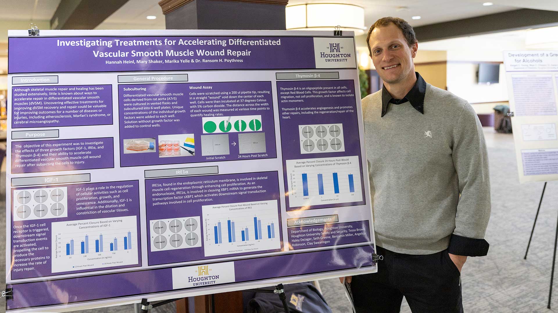 Professor Ransom Poythress standing next to his presentation board at the Faculty Scholarship Day at Houghton.