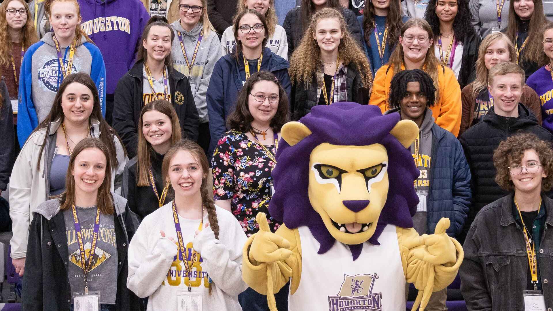 Houghton accepted students standing on bleachers with Luckey mascot during Accepted Student Day.