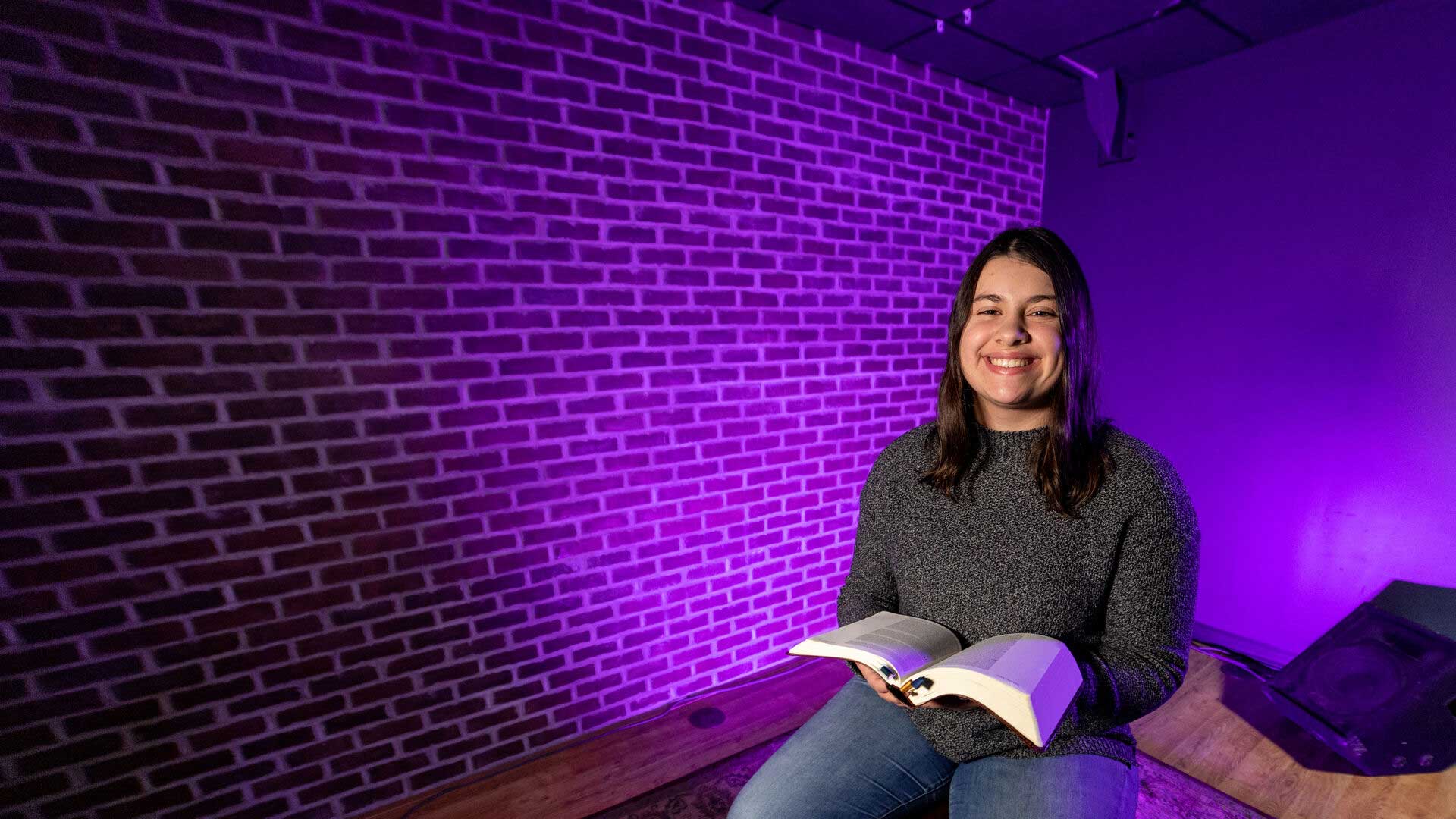 Houghton student Izzy Murch sitting with open bible on lap.