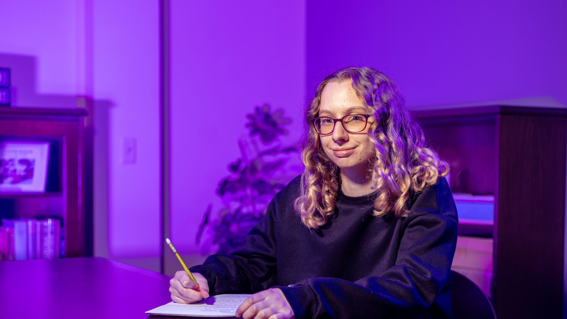 Houghton writing student Jennifer Page sitting at table with notebook and pencil.