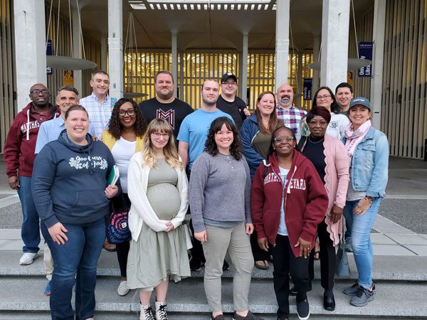 Participants of the Seventh Day Baptist General Conference workshop smiling at camera for a group photo while standing on stairs