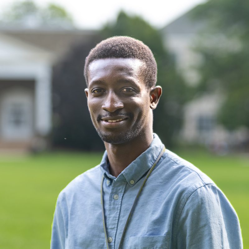 Houghton professor Babafemi Sorinolu standing outside on campus lawn.