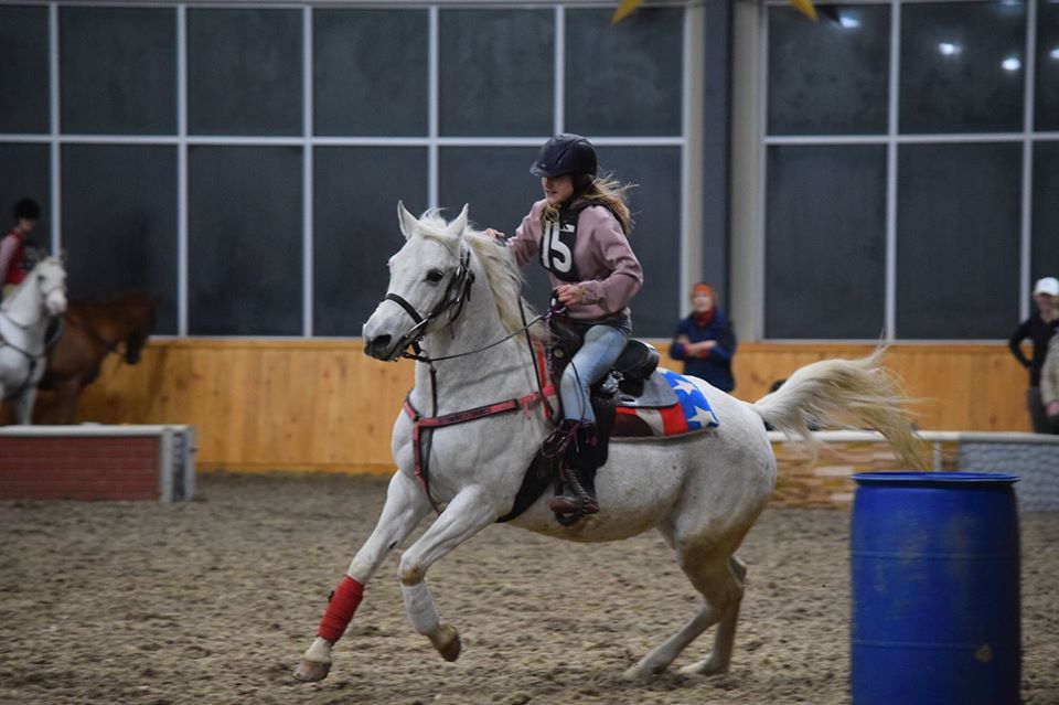 Competitor cantering horse around barrel during show