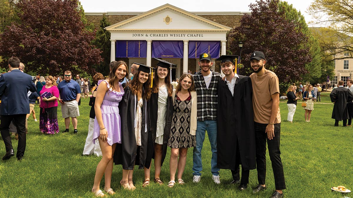 Houghton graduates and friends standing in front of the Wesley Chapel.