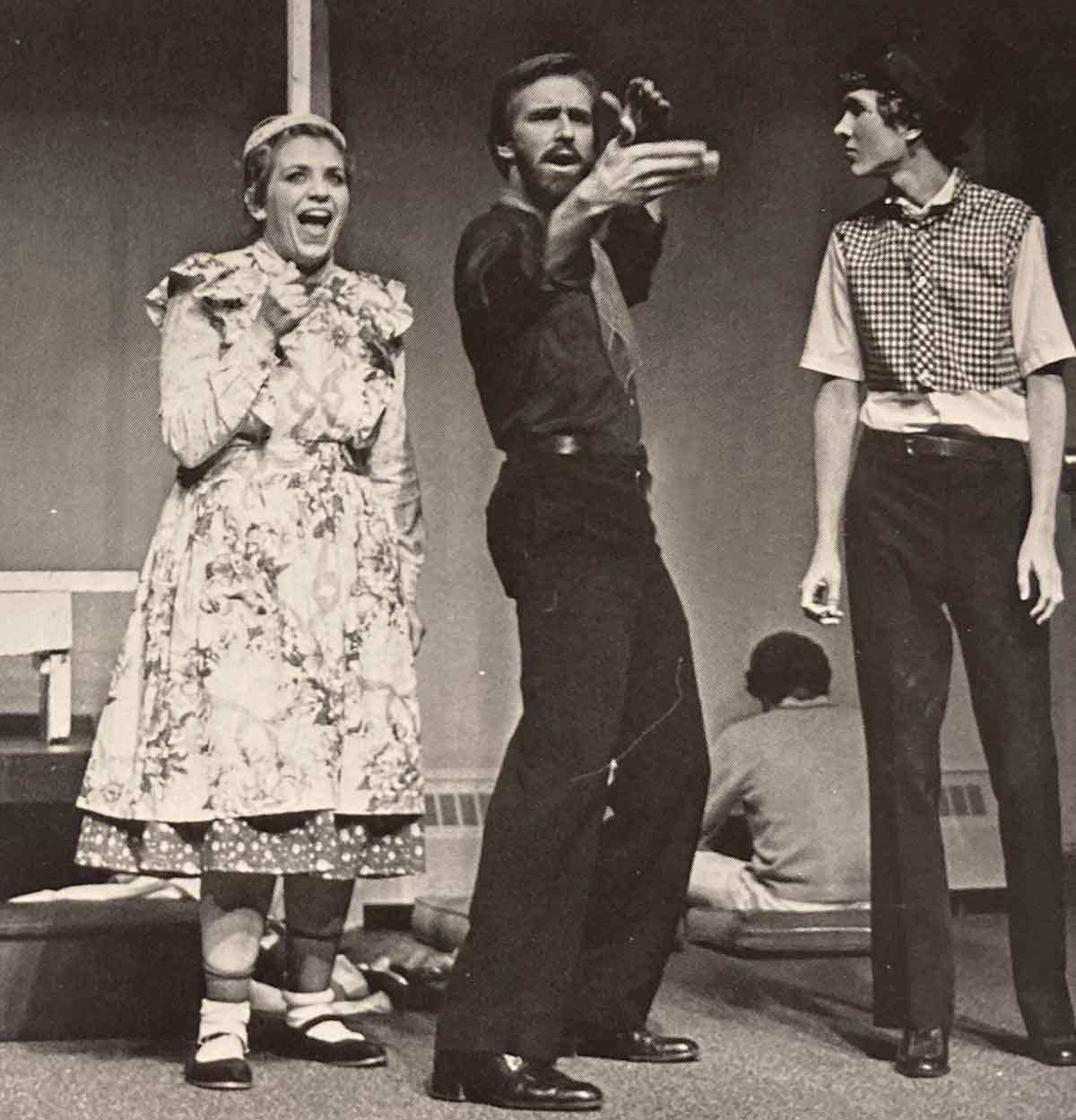 Black and white photo of three Houghton students in costume acting on stage.