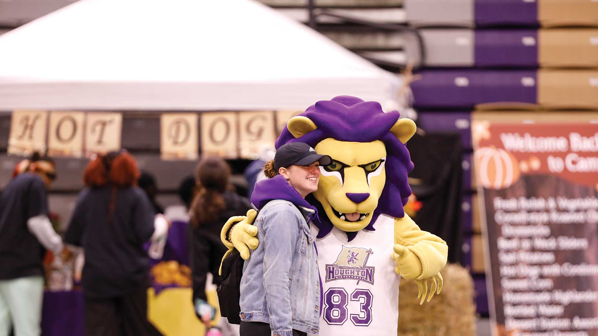 Student standing with Luckey the mascot during Houghton's homecoming.