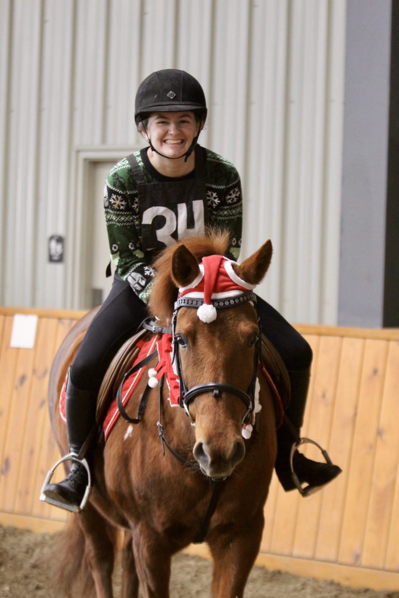 Student smiling in Christmas attire on lesson pony Rowan