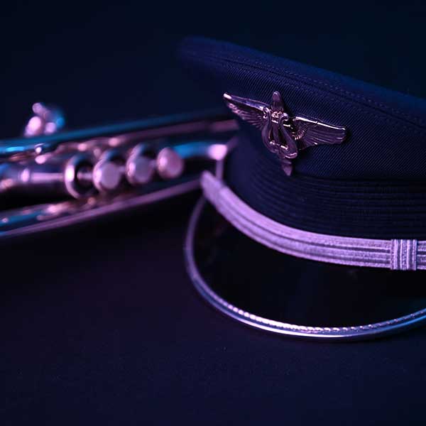 Military hat with woodwind instrument sitting on table with dark lighting.
