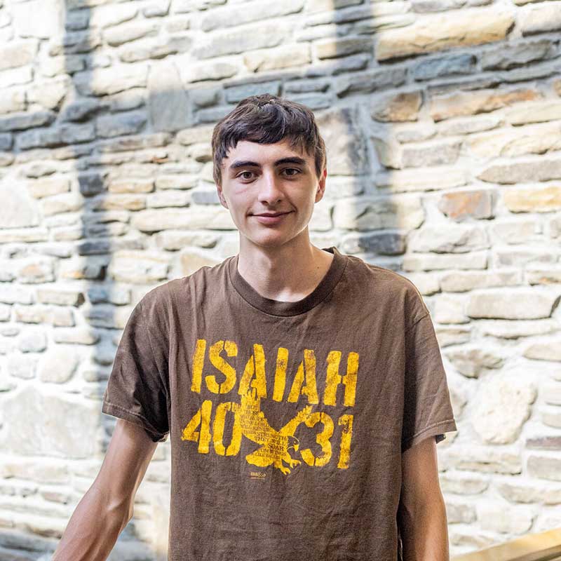 Houghton student Tobias Reiff with brown shirt and gold text, Isaiah 40:31.