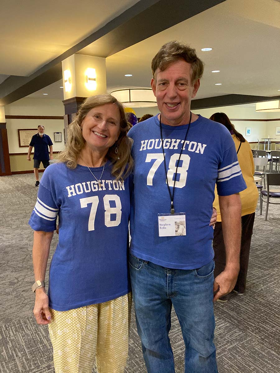 Two Houghton alumni wearing blue Houghton jerseys the the summer alumni reunion.