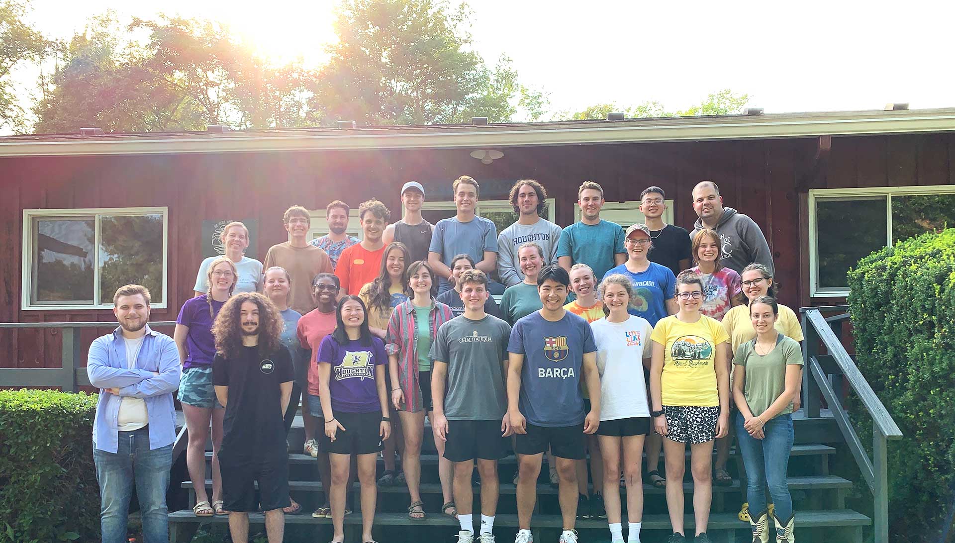 Houghton RA's and resident life staff standing on the steps in front of cabin.