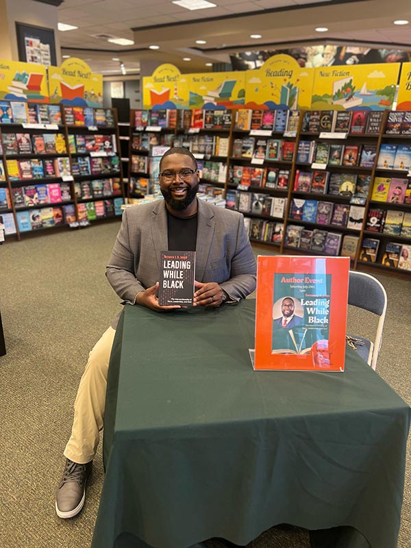 Torrance Jones sitting holding his new book at local bookstore.