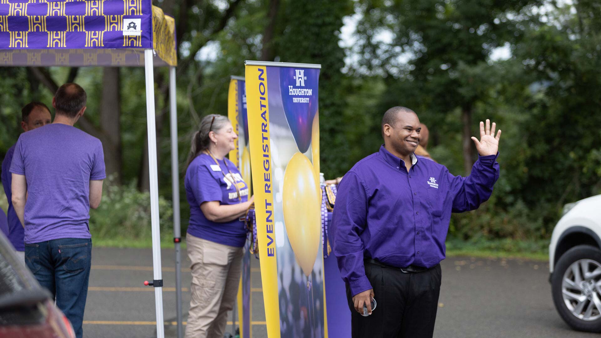Houghton President Wayne Lewis waving at cars as they come in for move-in day.