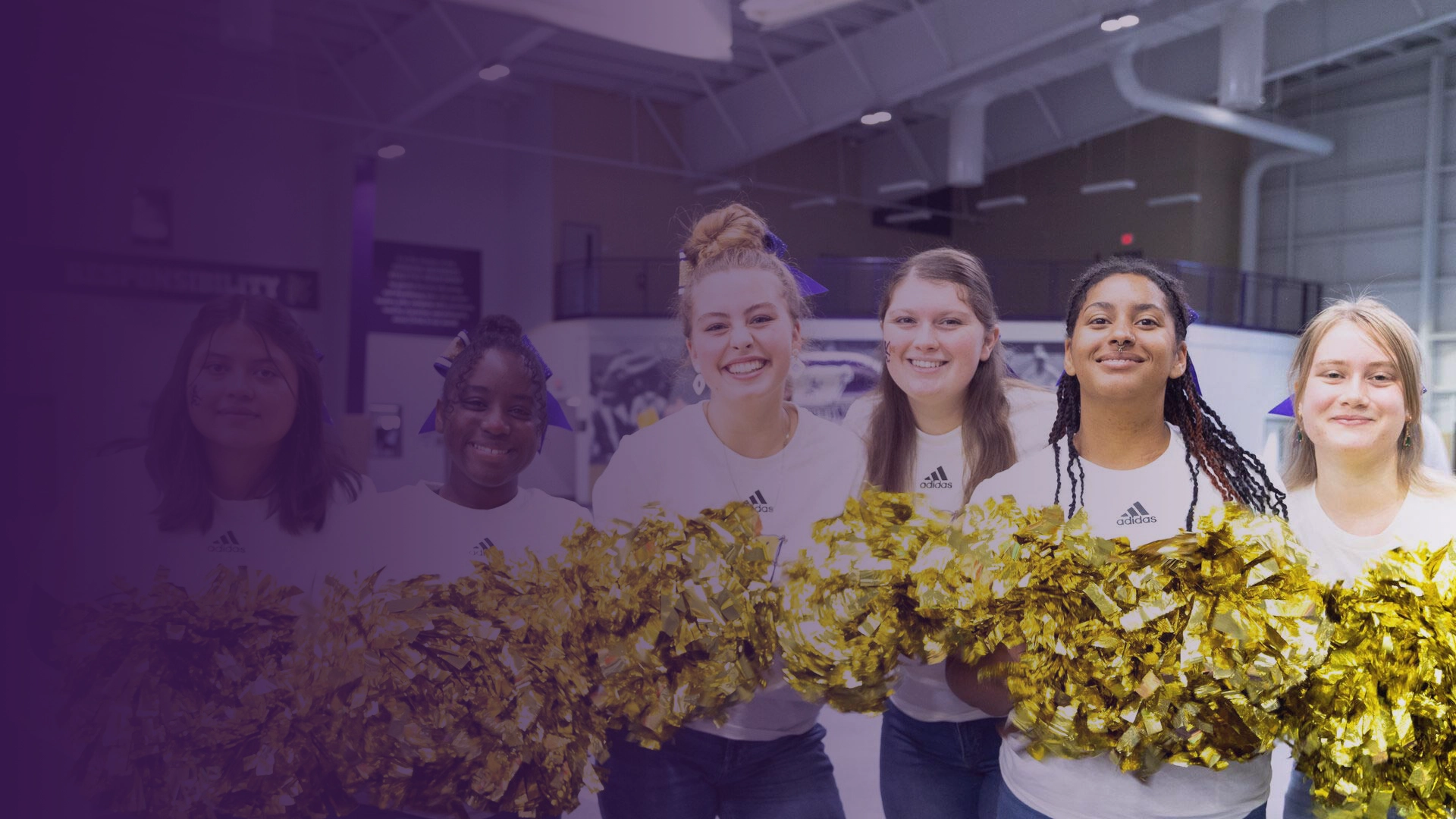 Six Houghton students standing with shimmery gold pom poms during Homecoming weekend.