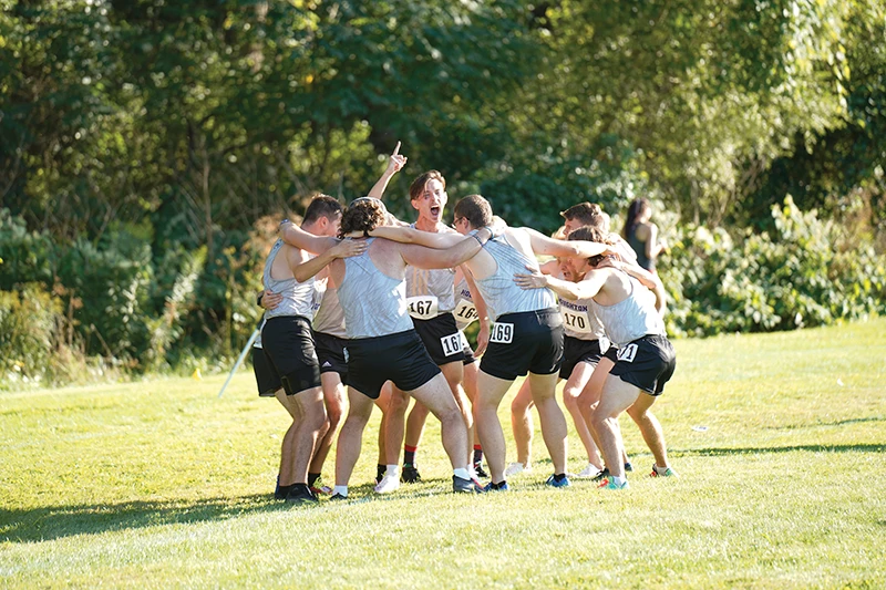Houghton men's cross country team cheering together in a huddle.