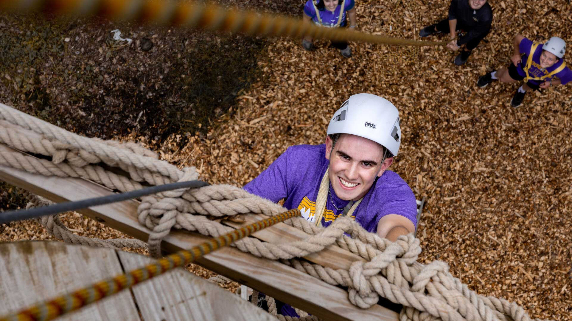 Houghton student climbing rope net at EPIC Adventures Ropes Course.