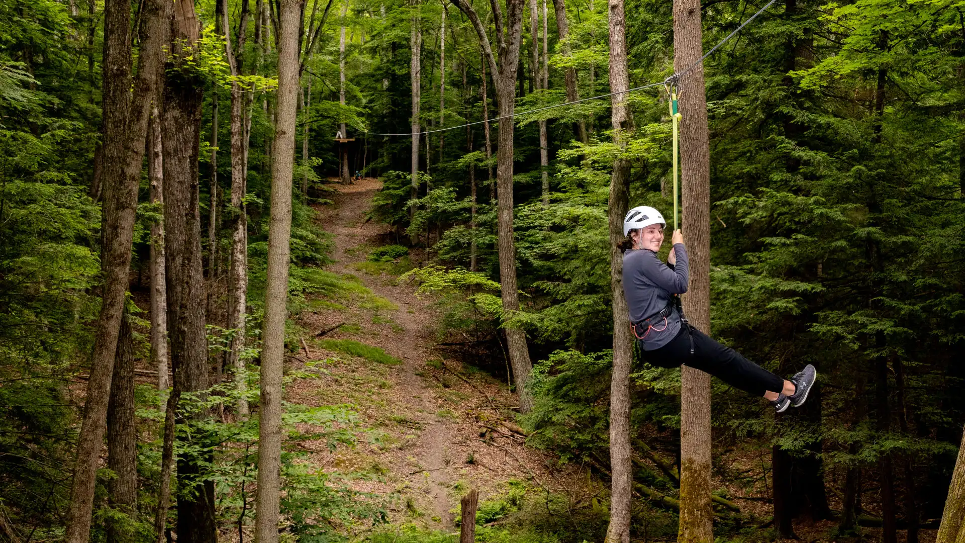 Houghton student riding zipline at the EPIC Adventures ropes course.
