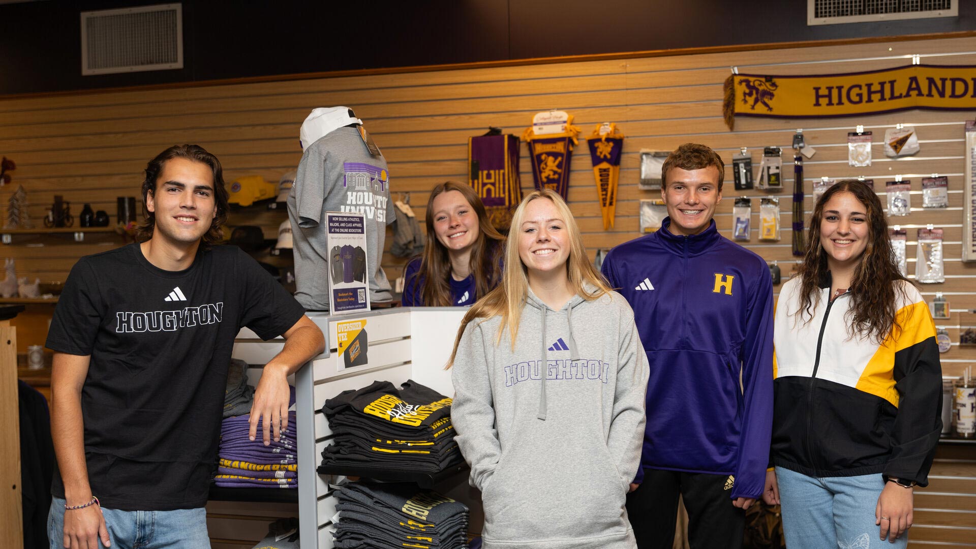 Five Houghton students wearing Houghton Highlander gear standing in the Highlander Shop.