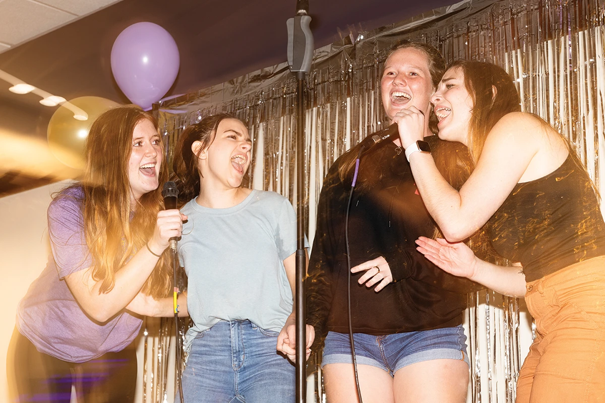 Four Houghton students standing on stage singing during Homecoming.