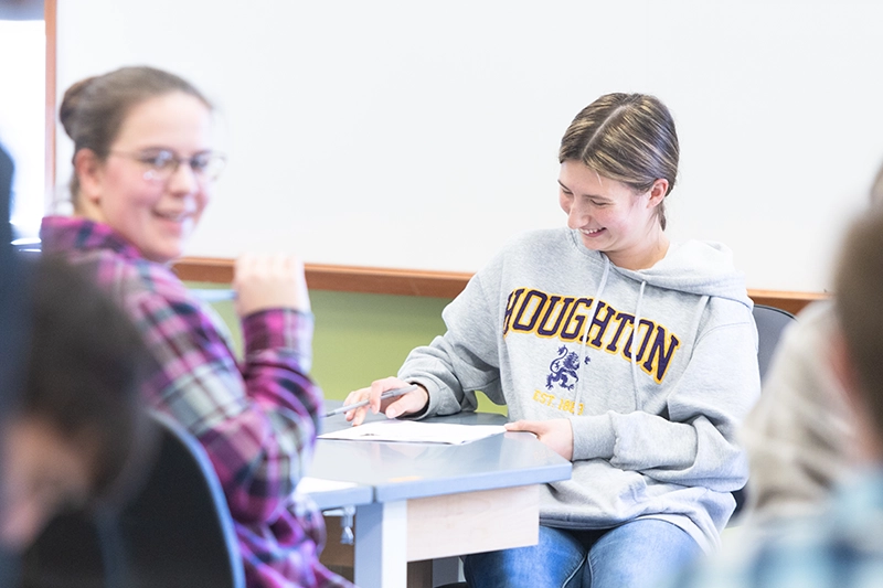 Two Houghton students sitting at lab table during class, one wearing a Houghton sweatshirt.