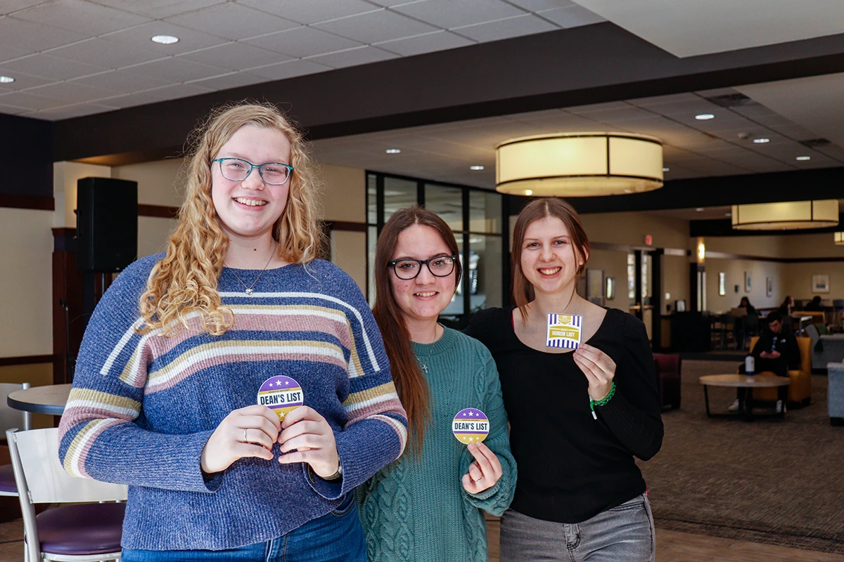 Three Houghton academic honors students standing together with sticker badges.