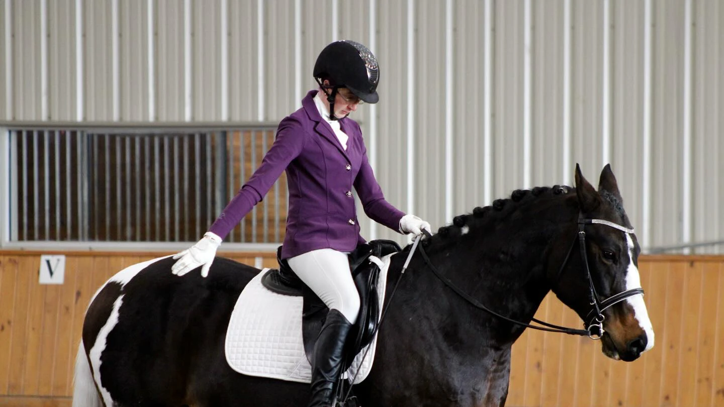 Houghton equestrian student riding horse in equestrian center arena.