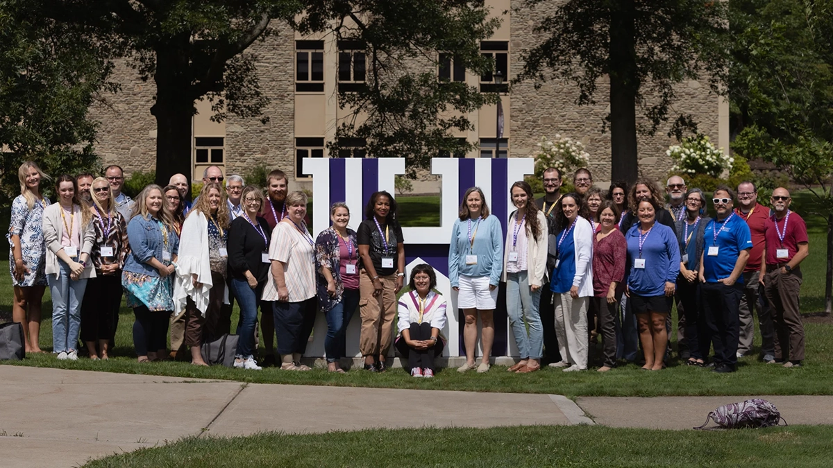 Attendees standing outside by the Houghton H at the Christian School Summer Symposium.