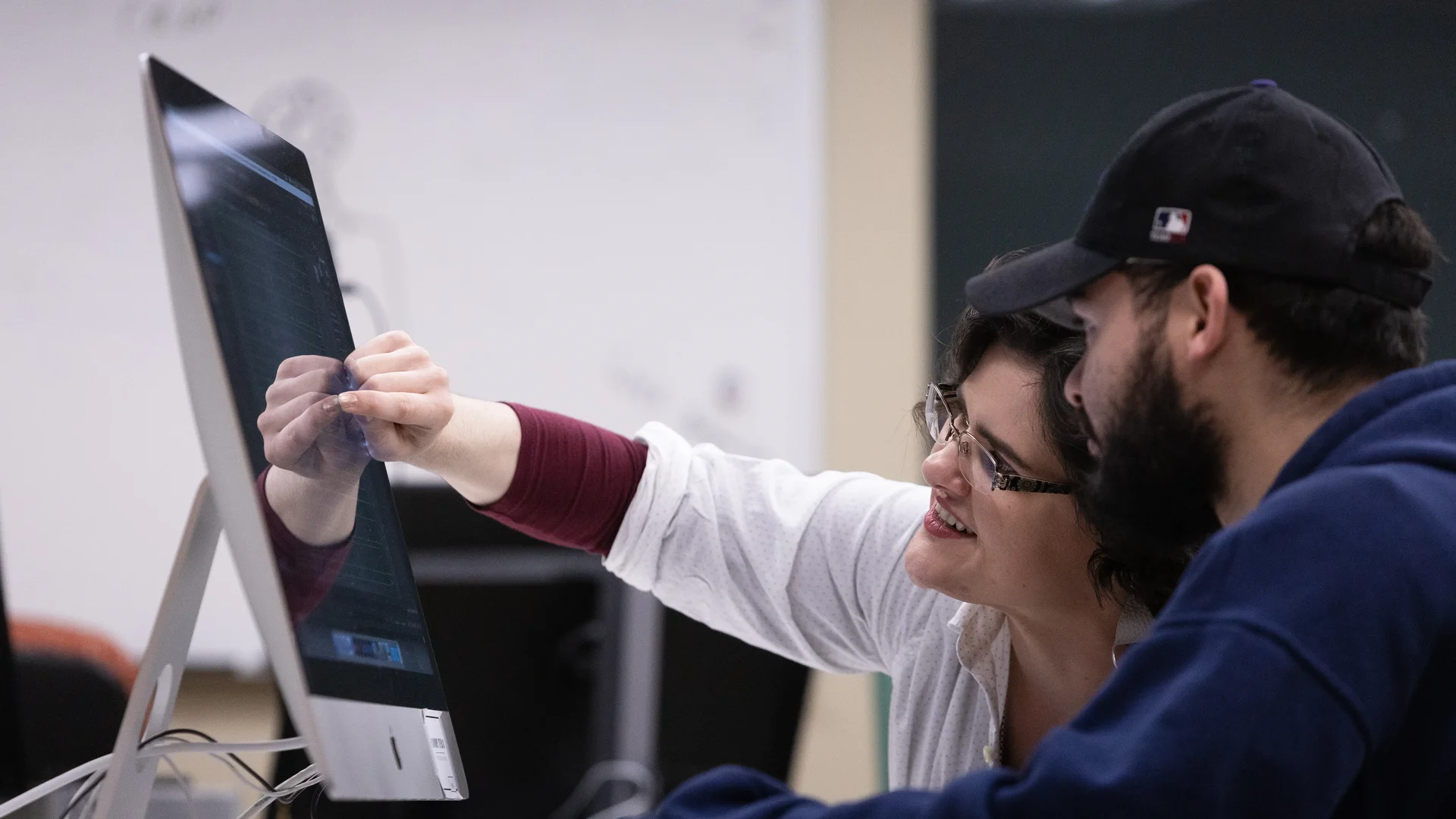 Houghton professor working with student in mac lab during media arts class.