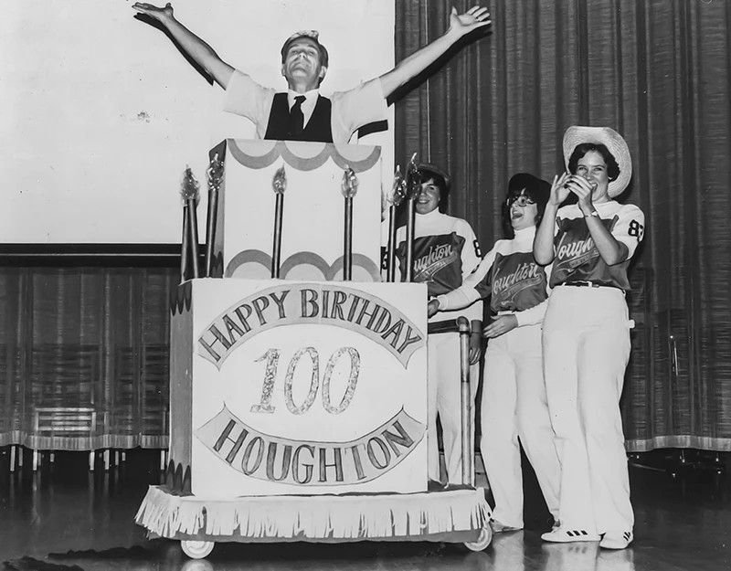 Houghton president emeritus Dan Chamberlain jumping out of pretend 100th anniversary cake for Houghton.