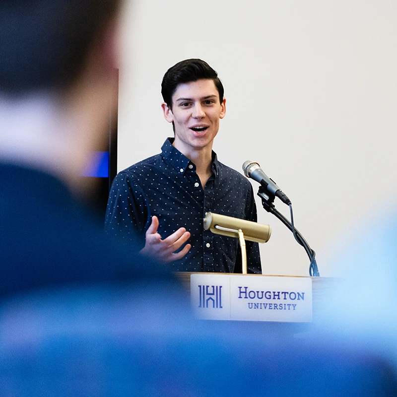 Recent Houghton alumnus Cody Johnson speaking at podium.