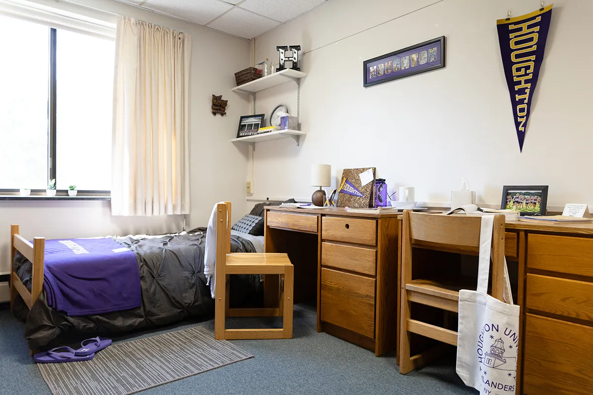 Interior view of a room in Lambein including a desk, bed, shelves and decoration.