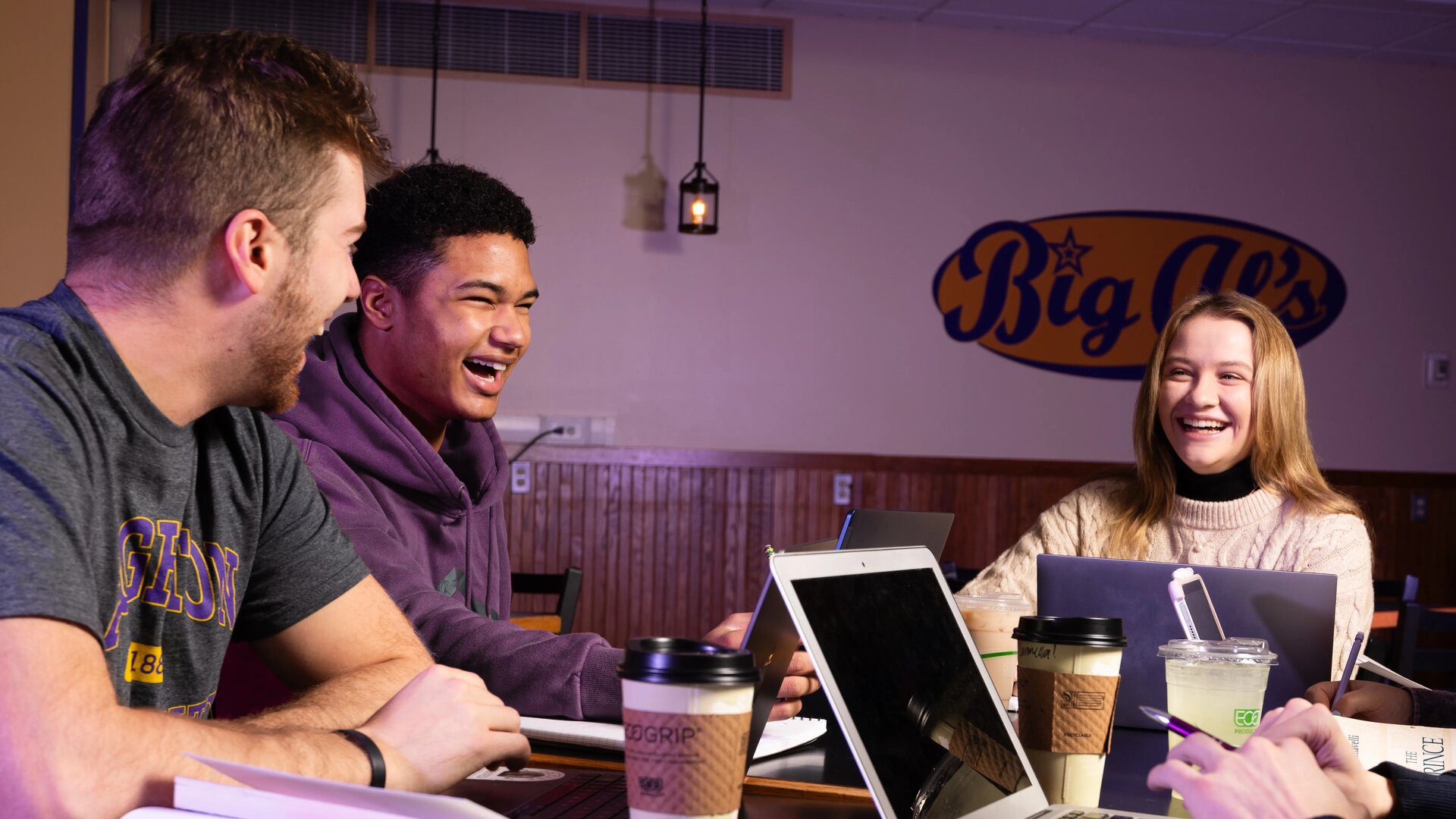 Three Houghton students sitting at table with laptops.