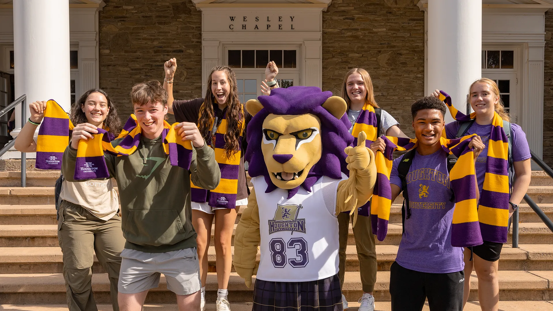 Luckey on steps with Houghton students holding their first year scarves.