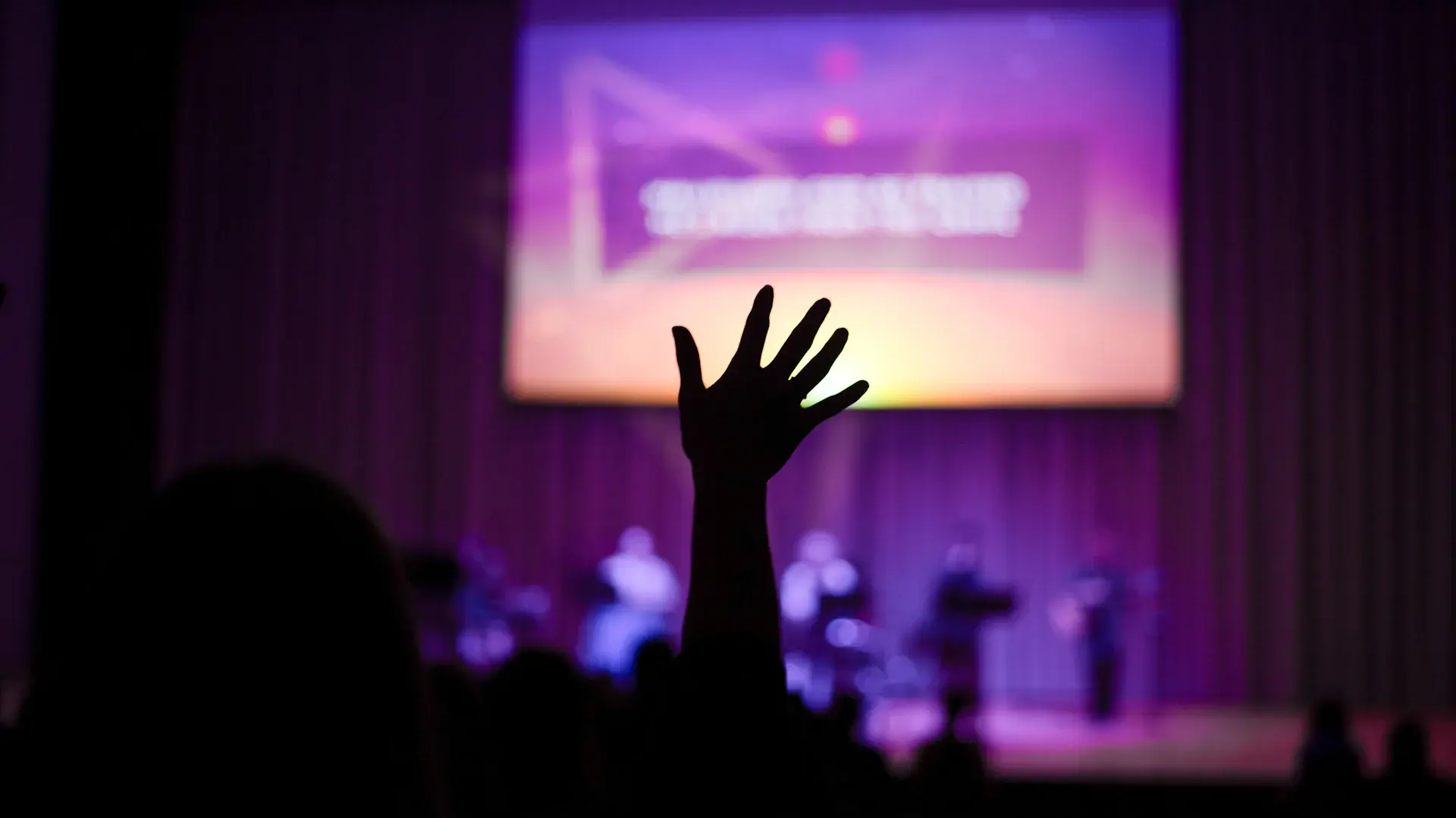 Houghton student lifting their hand in praise during KOIN worship service.