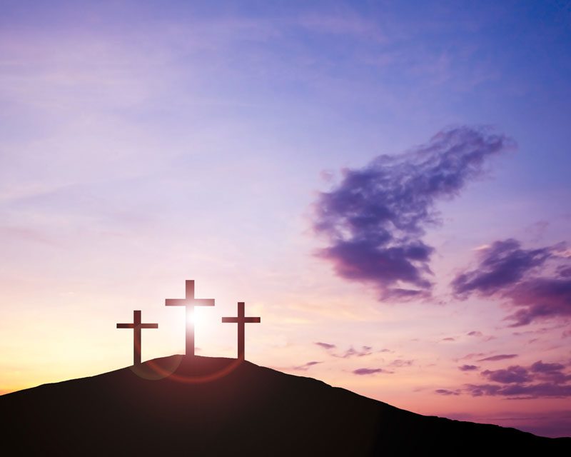 three crosses on a hilltop at sunrise