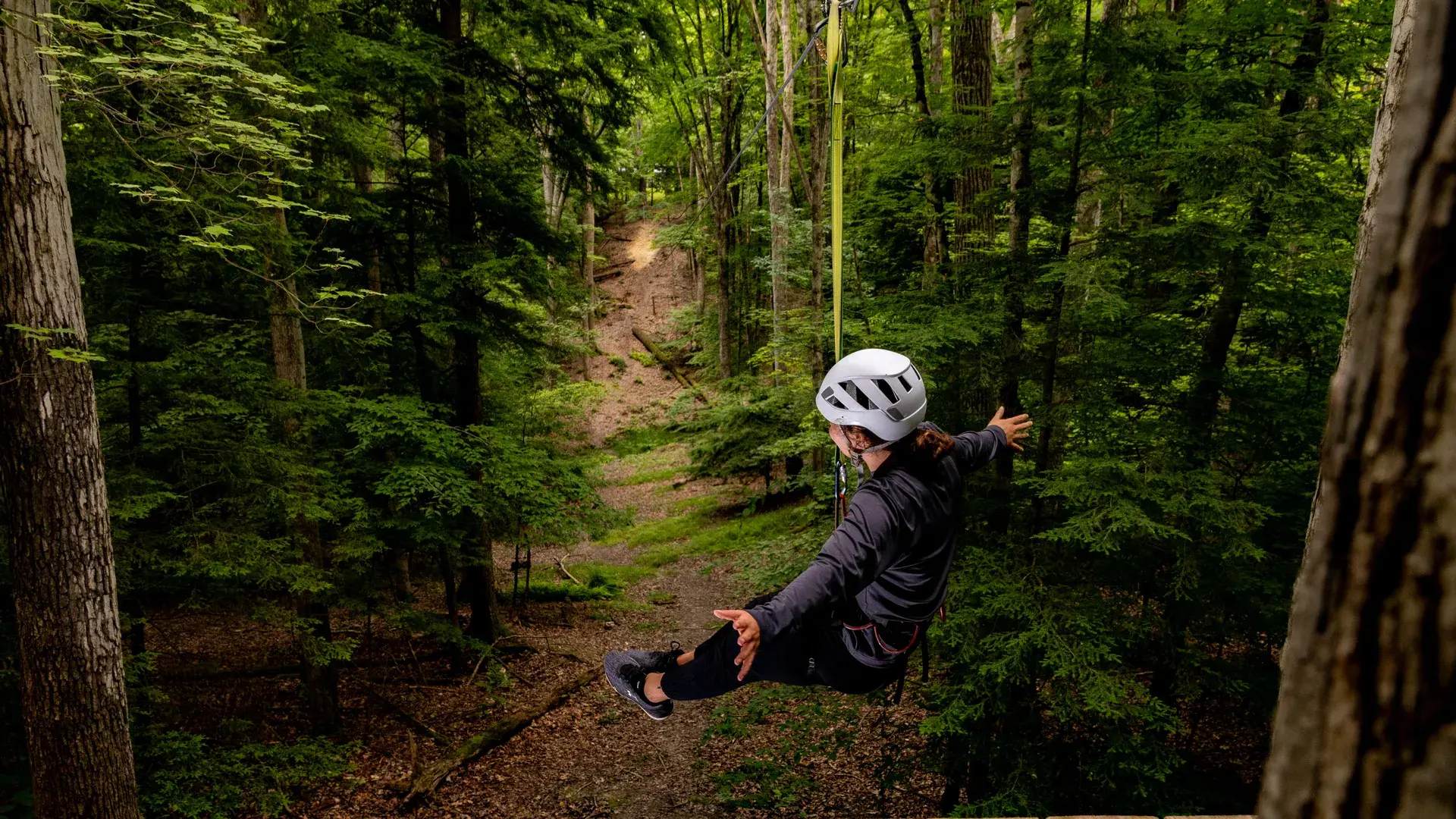 Houghton student with arms extended getting ready to ride zipline on Epic Adventure ropes course.