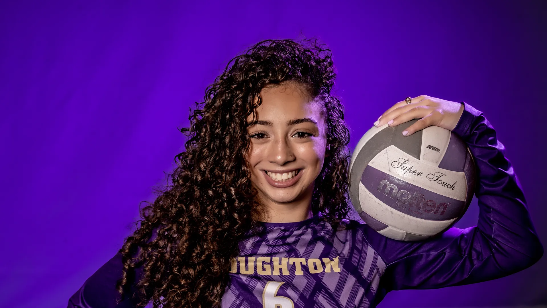 Houghton athlete and sport, recreation and wellness management major Natalie Rivera in uniform holding volleyball.