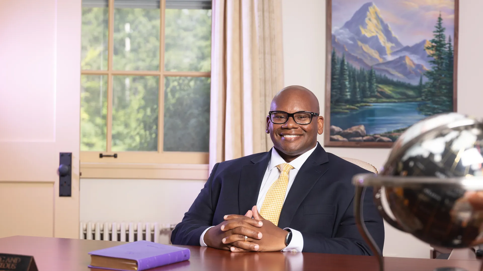 President Lewis of Houghton University sitting at desk with purple bible.