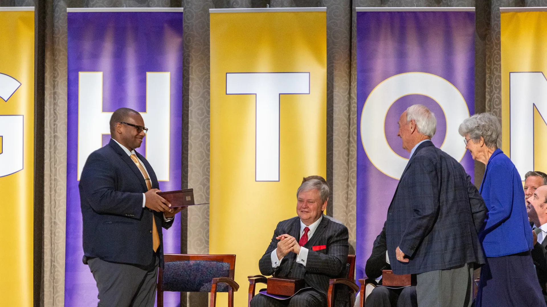 Houghton University president Dr. Wayne Lewis presenting an alumni award to Doug and Barbara Kindschi.