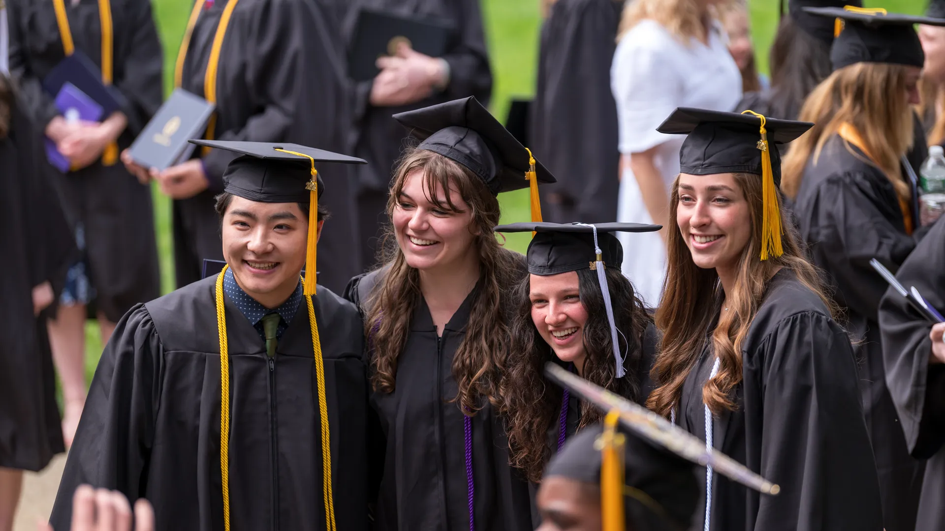 Four Houghton graduates standing together for picture in graduation regalia.