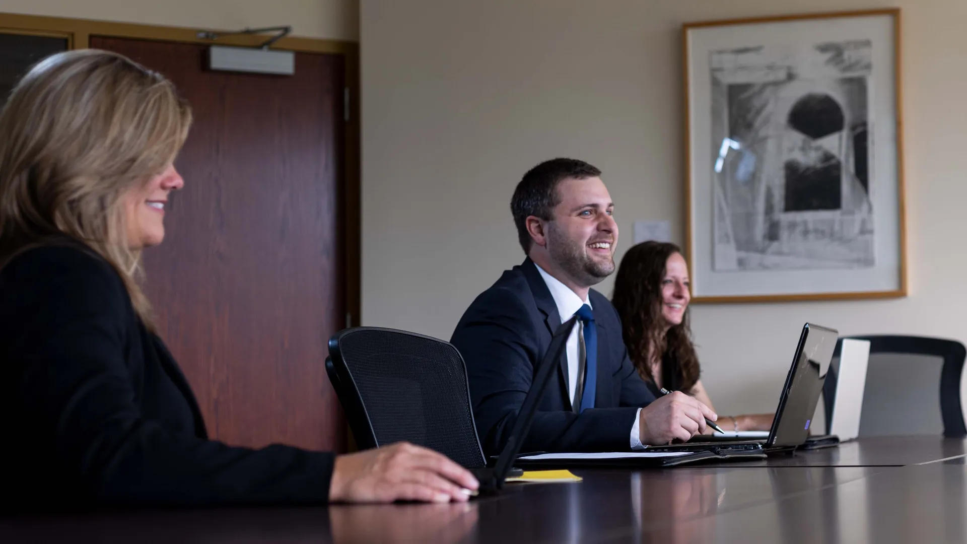 Three Houghton MBA students sitting at large conference table.