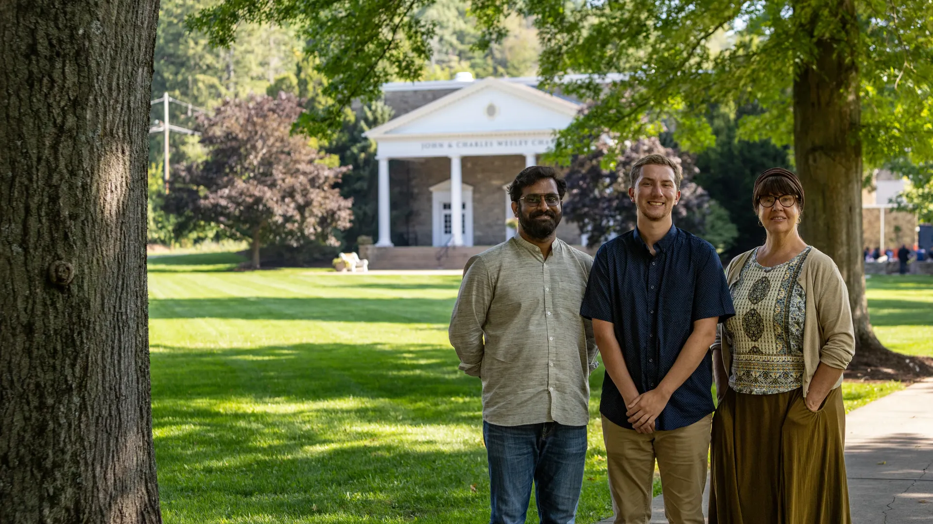 Three new Houghton University faculty members standing on the quad.