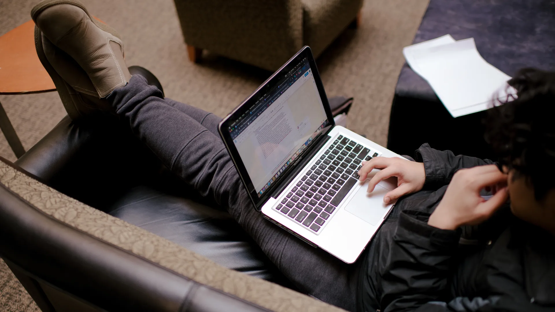 Houghton student lounging on couch with laptop.