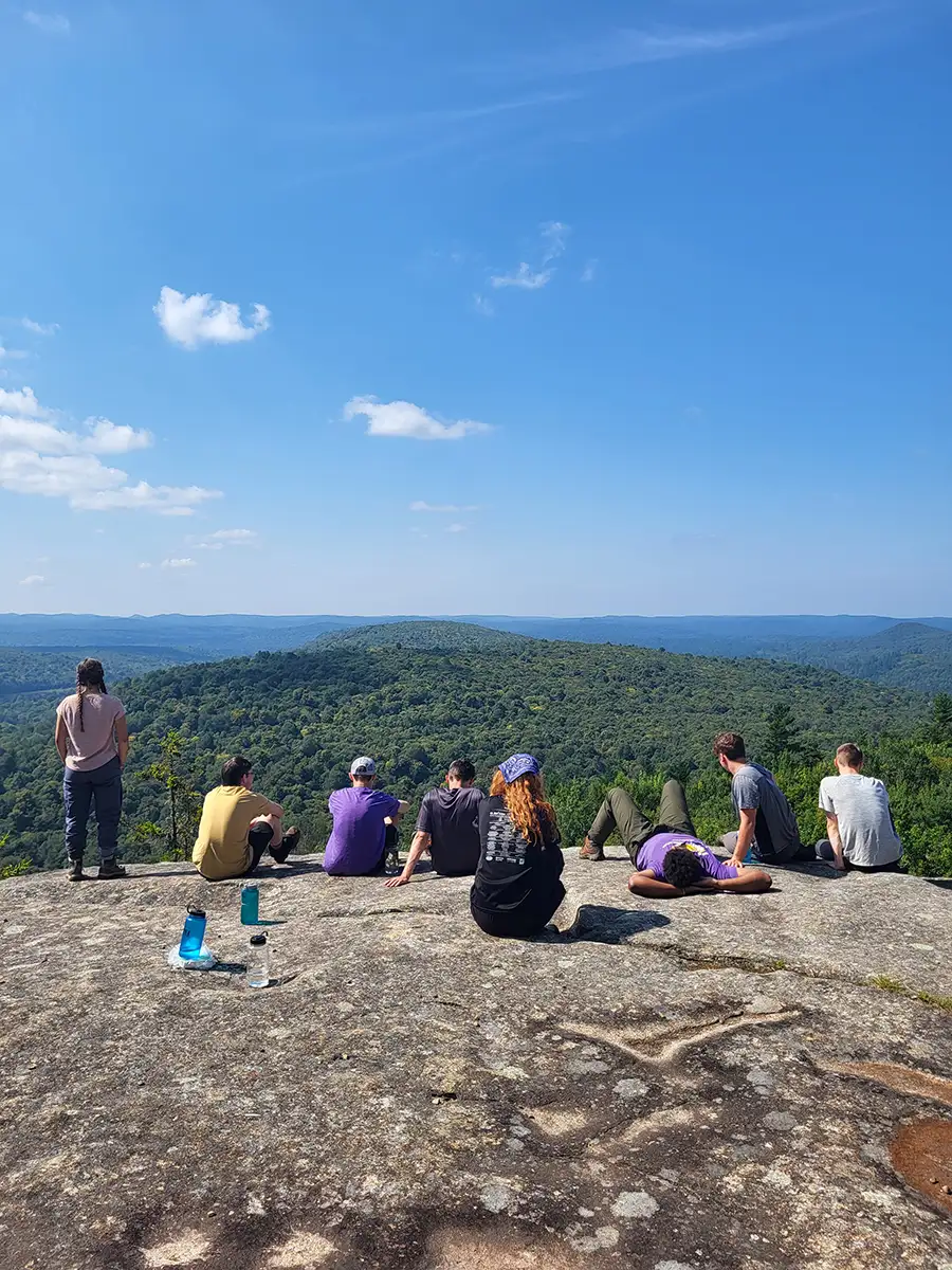 Houghton Highlander Wilderness Adventure students sitting on cliff edge on mountaintop.