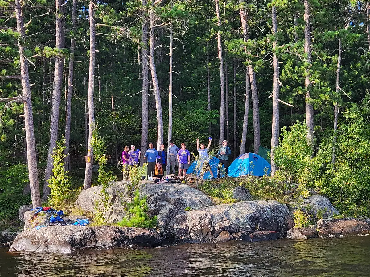Houghton Highlander Wilderness Adventure students waving from shoreline.