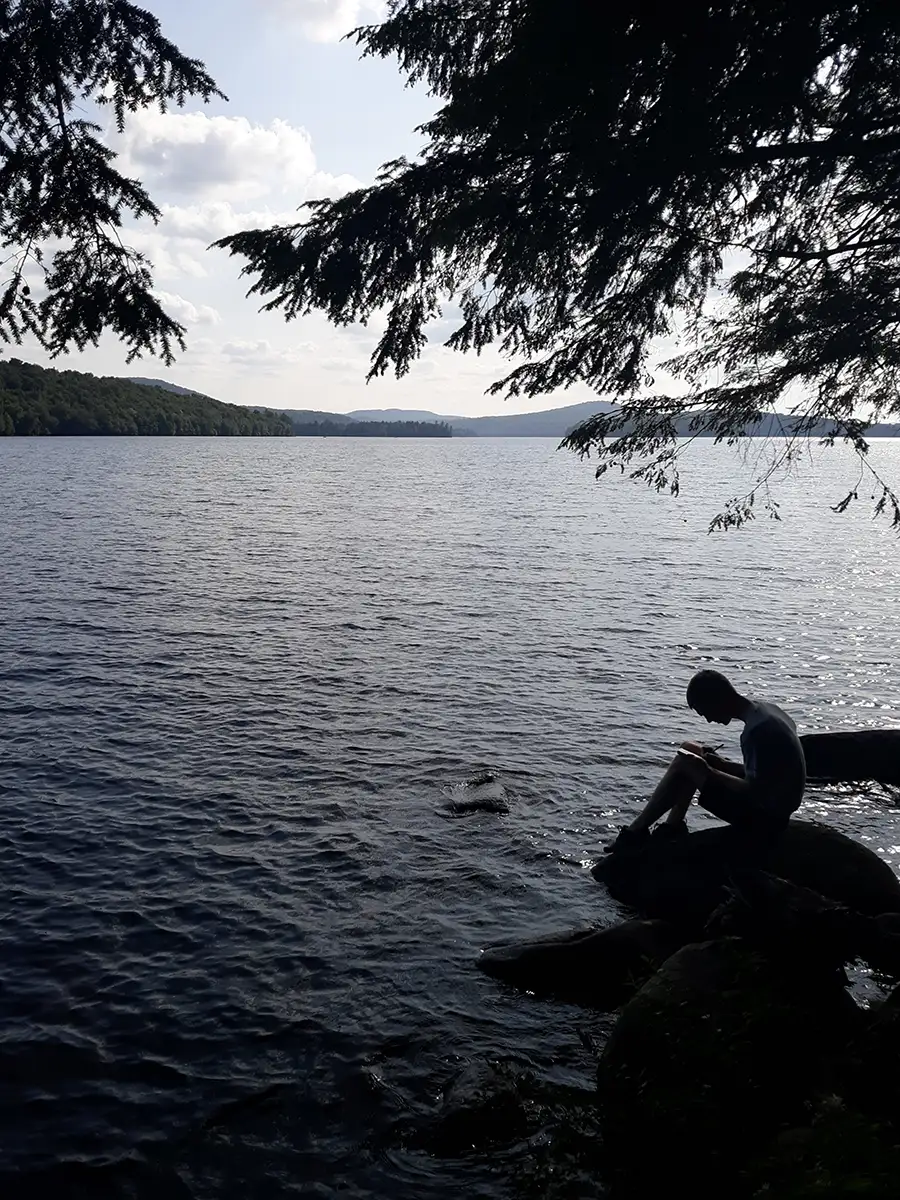 Houghton Highlander Wilderness Adventure student sitting by lake.